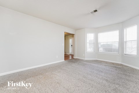 a spacious living room with carpet and windows
