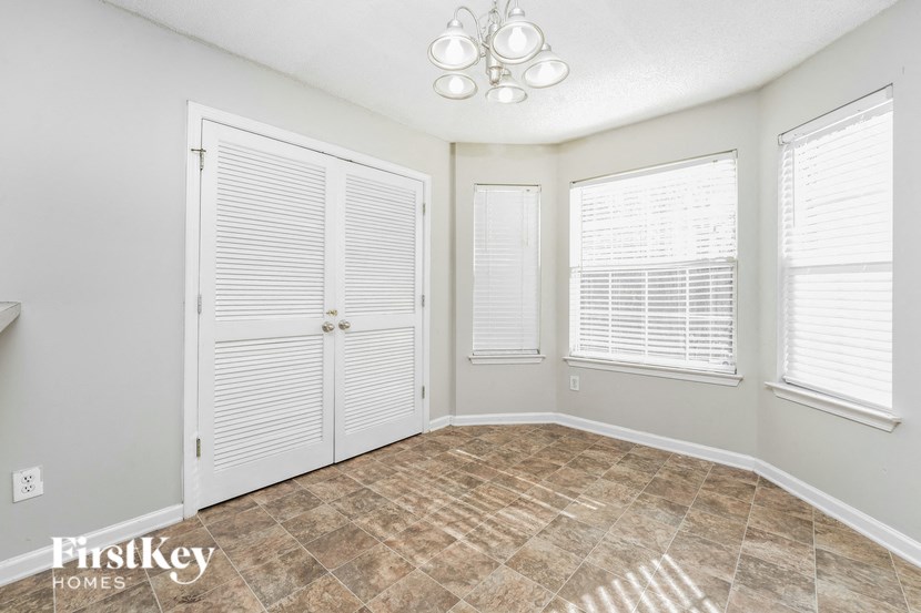 a dining room with white shutters and a large window