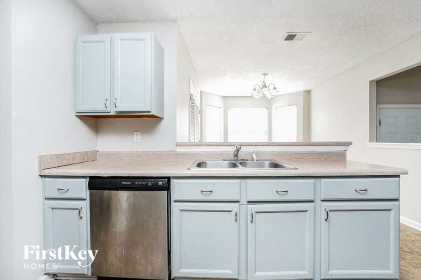 a white kitchen with white cabinets and a stainless steel sink