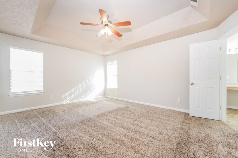 a spacious living room with carpet and a ceiling fan