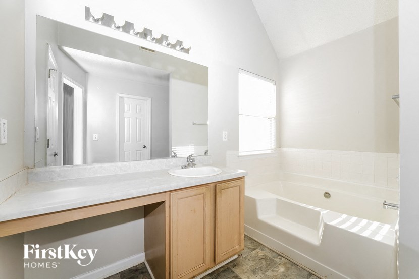 a bathroom with a sink and a tub and a large mirror