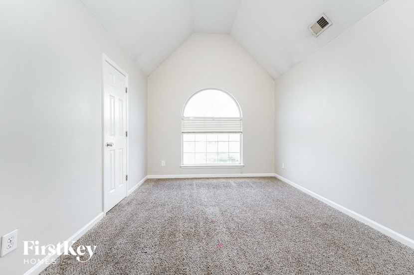 an empty room with white walls and carpet and a window