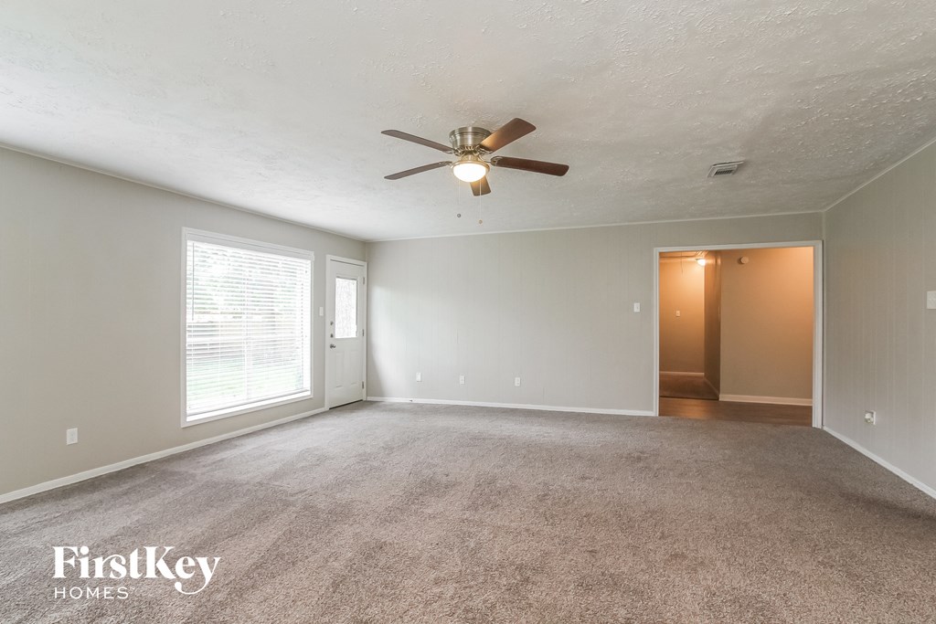 the living room of an empty house with a ceiling fan