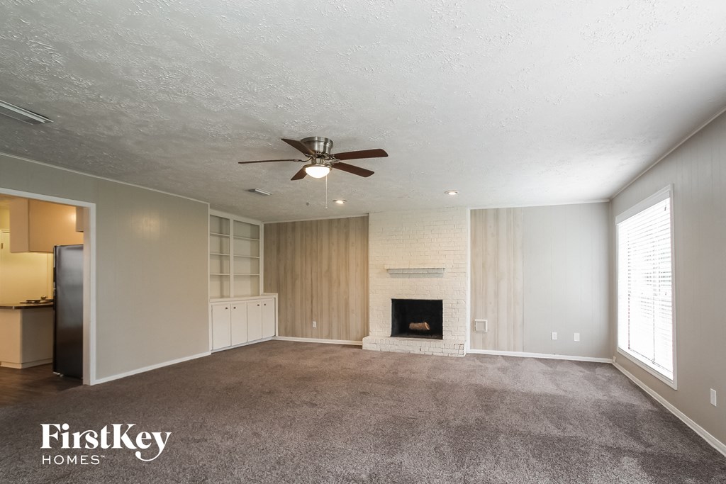 an empty living room with a fireplace and a ceiling fan