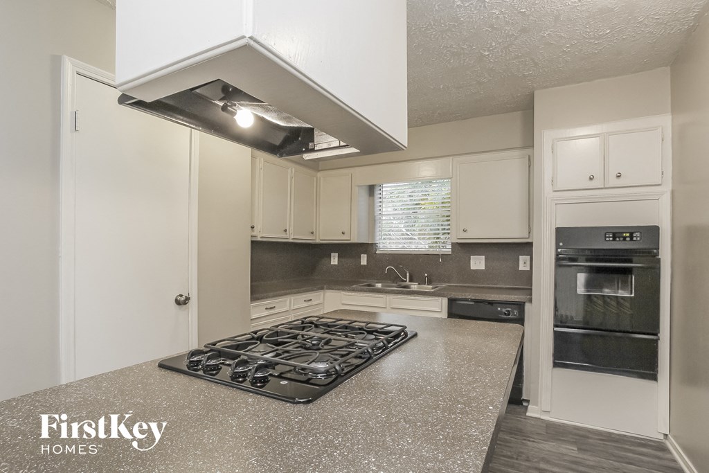 a kitchen with white cabinets and granite counter tops and a stove top oven