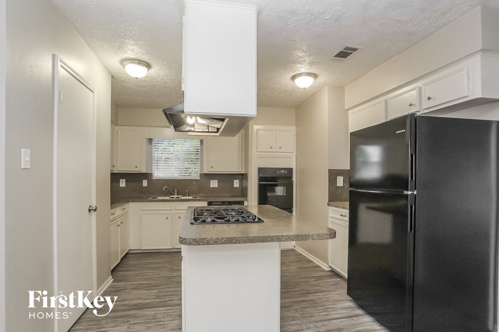 a kitchen with white cabinets and black appliances and a counter top
