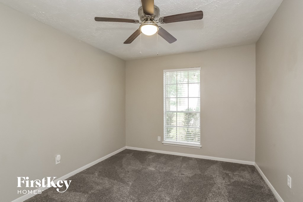 an empty room with a ceiling fan and a window