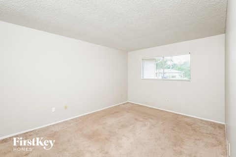 a bedroom with carpet and a window