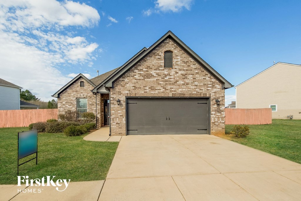 A house with a stone facade and a garage door is for sale.
