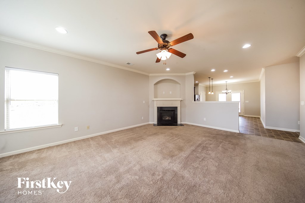 A spacious living room with a fireplace and a ceiling fan.