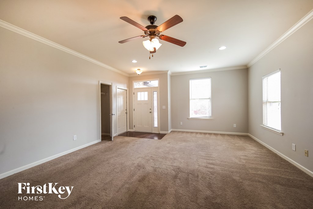 A spacious room with a ceiling fan and carpeted floor.