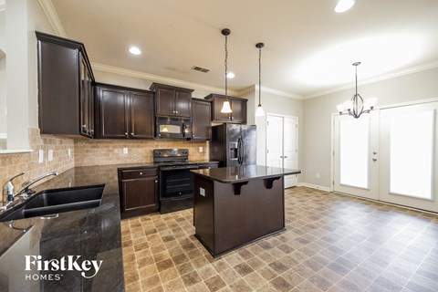 A kitchen with a black counter top and brown cabinets.