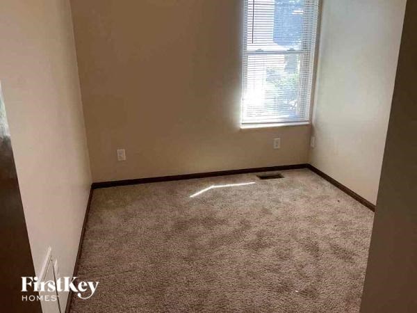 A carpeted room with a window and a wall socket.