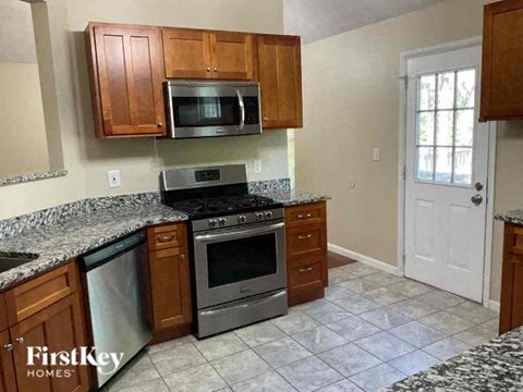 A kitchen with granite countertops and wooden cabinets.