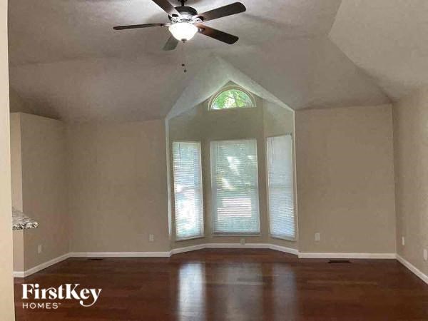 A room with a ceiling fan and a large window.