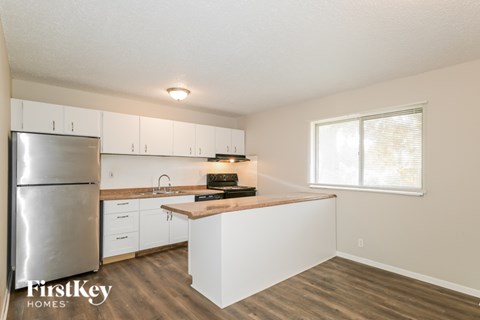 A kitchen with a refrigerator, sink, and cabinets.