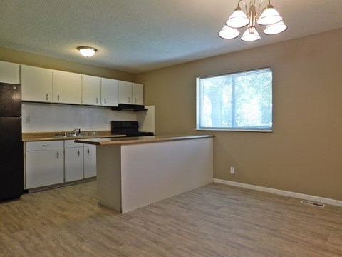 A kitchen with white cabinets and a black refrigerator.