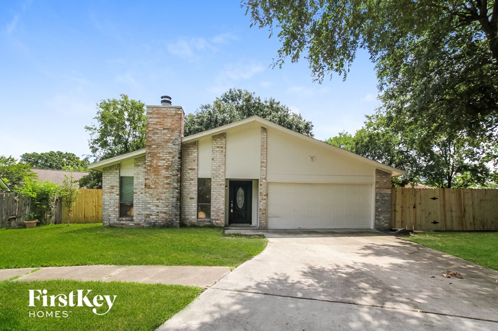 the front of a white house with a garage door and lawn