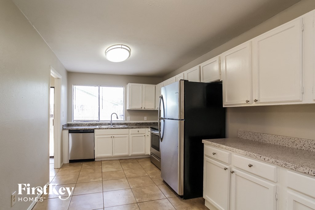 a kitchen with white cabinets and a black refrigerator