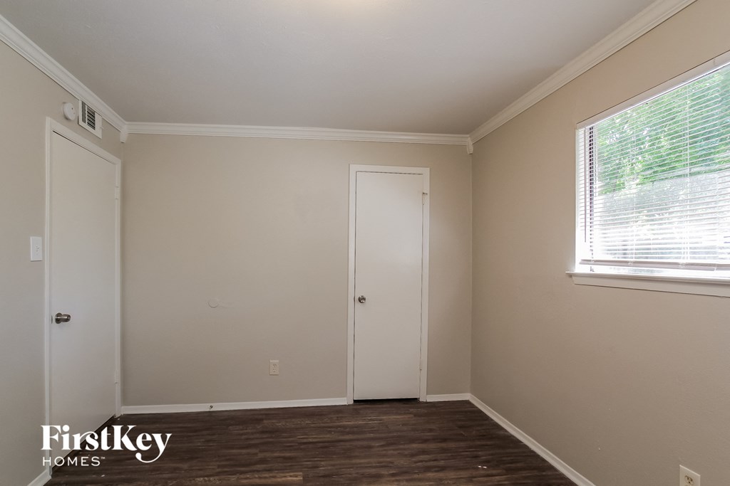 a bedroom with white walls and a window and a door