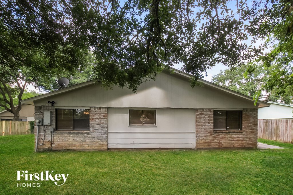 a white and brick house with a yard and trees