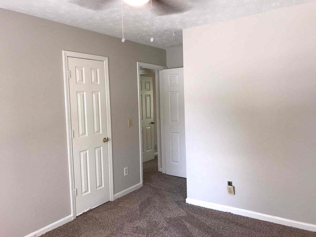 A room with a white door and a carpeted floor.