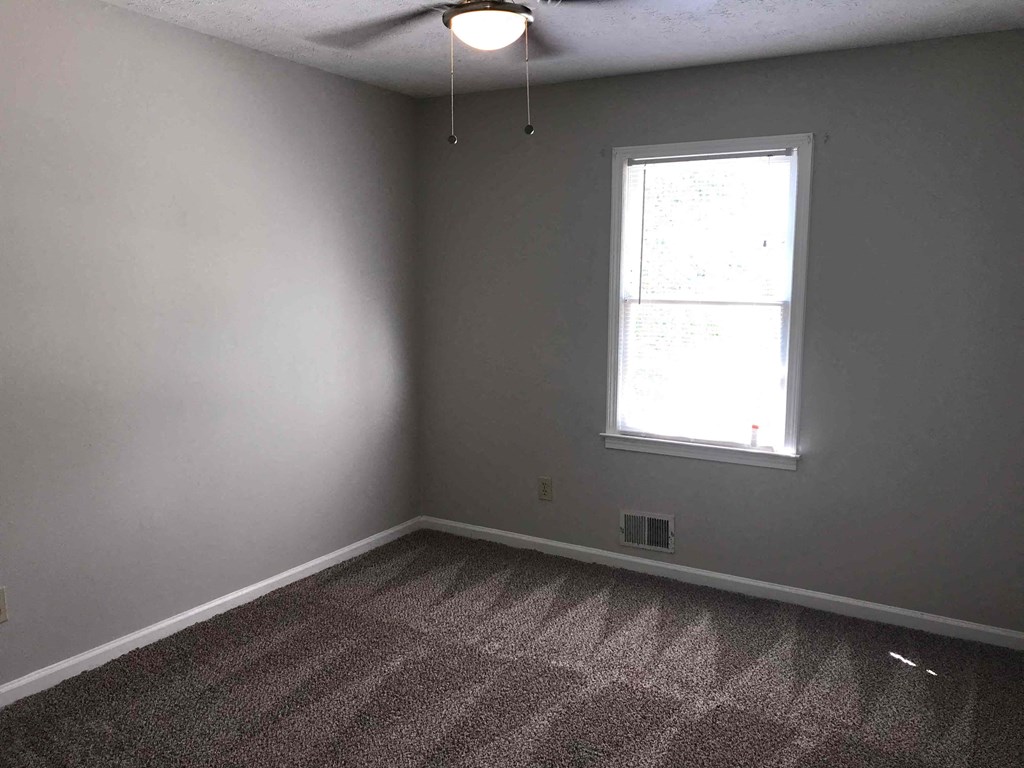 A room with a carpeted floor and a window.