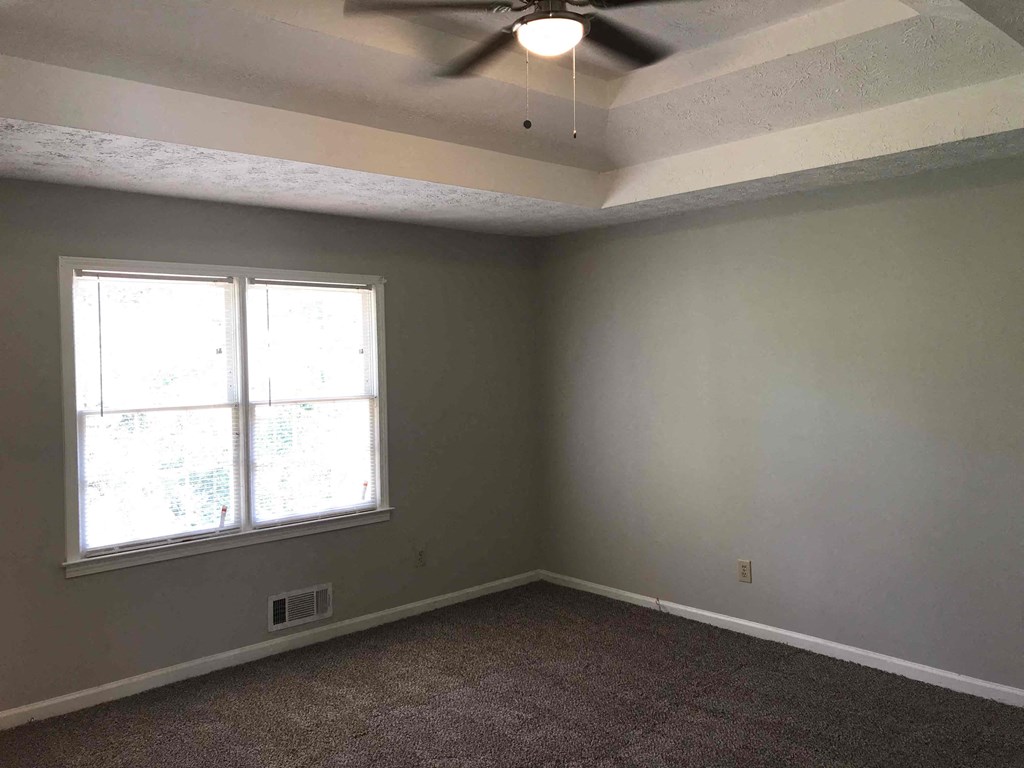 A room with a ceiling fan and a window.