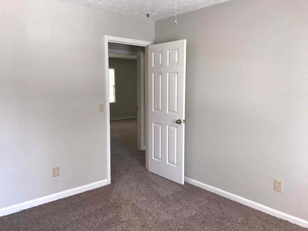 A room with a white door and carpeted floor.