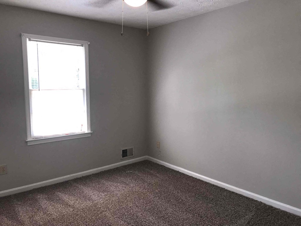 A room with a window and carpeted floor.