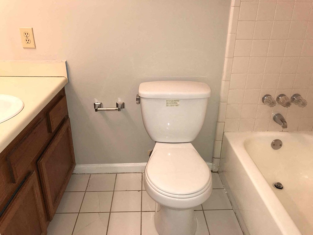 A white toilet in a bathroom with a white tub and sink.