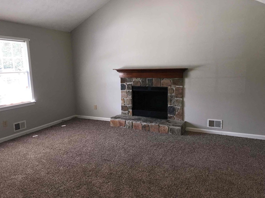 A room with a fireplace and carpeted floor.