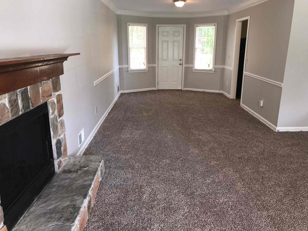 A living room with a fireplace and carpeted floor.