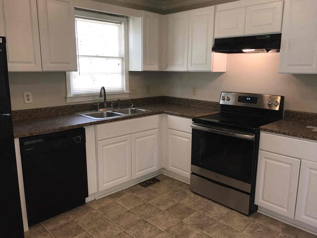 A kitchen with black appliances and white cabinets.