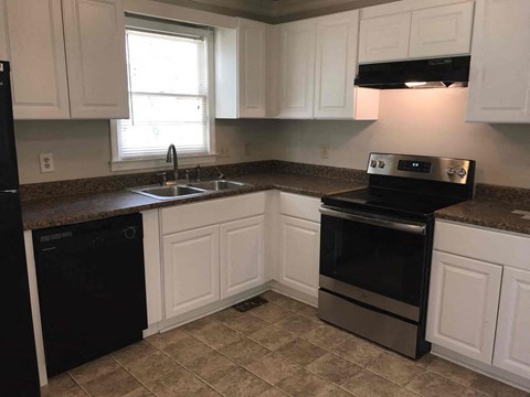 A kitchen with black appliances and white cabinets.