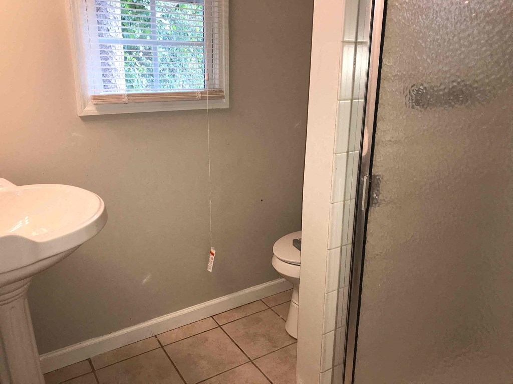 A bathroom with a toilet, sink, and shower.