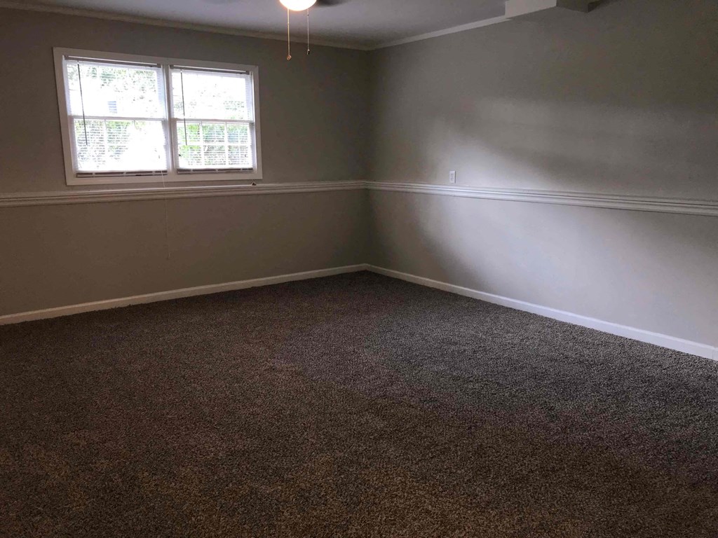A room with a carpeted floor and a window.