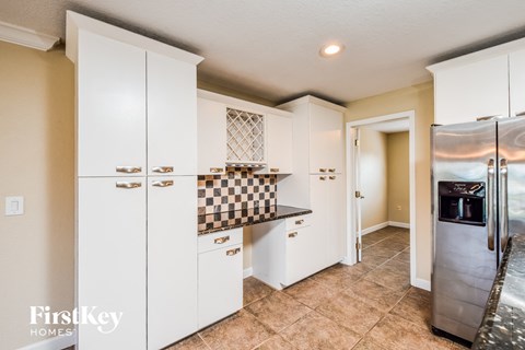 A kitchen with white cabinets and a checkered backsplash.