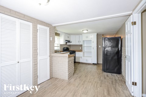 A kitchen with white cabinets and a black refrigerator.