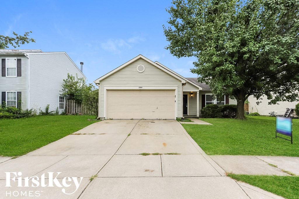 a white house with a white garage door on the side of a driveway