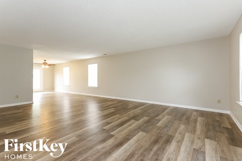 the living room and dining room with wood floors and white walls