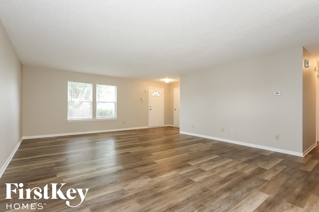 the living room and dining room with wood floors and white walls