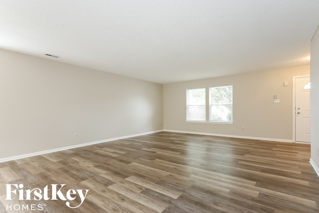 the spacious living room with wood floors and white walls