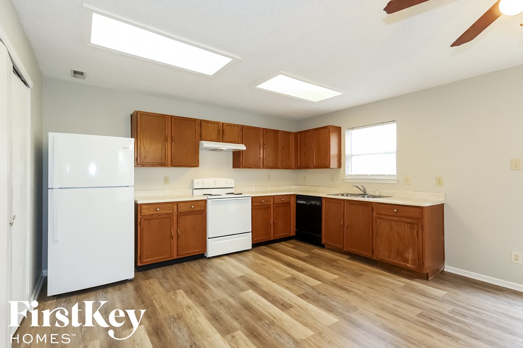 an empty kitchen with white appliances and wooden cabinets