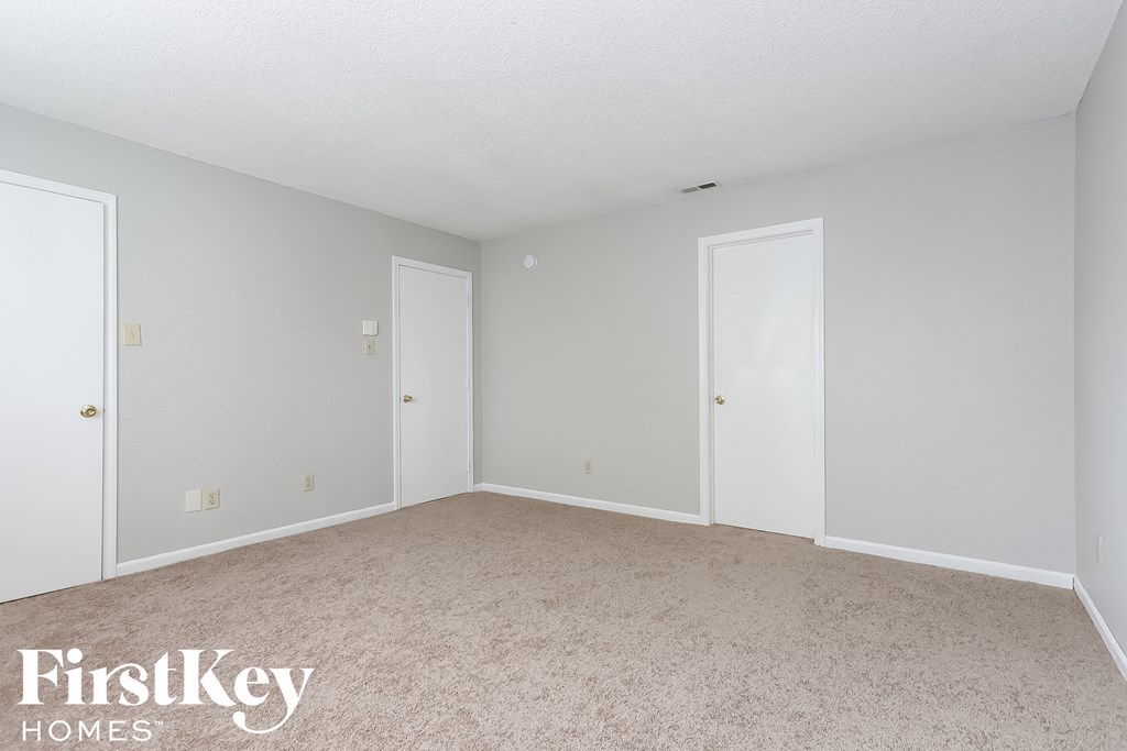 a bedroom with two doors and a carpeted floor