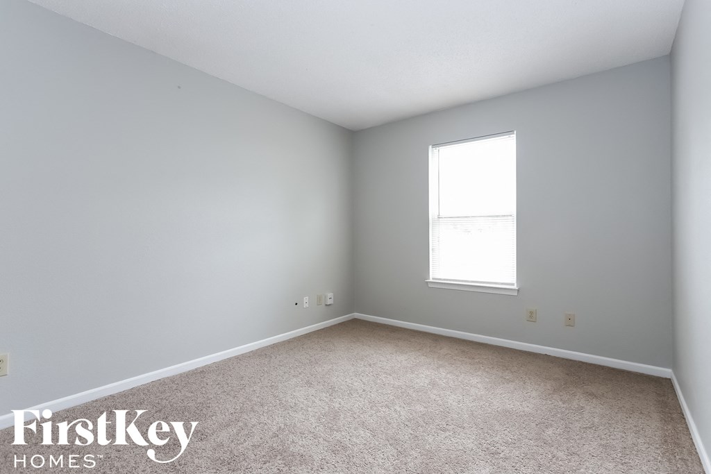 a bedroom with white walls and a window