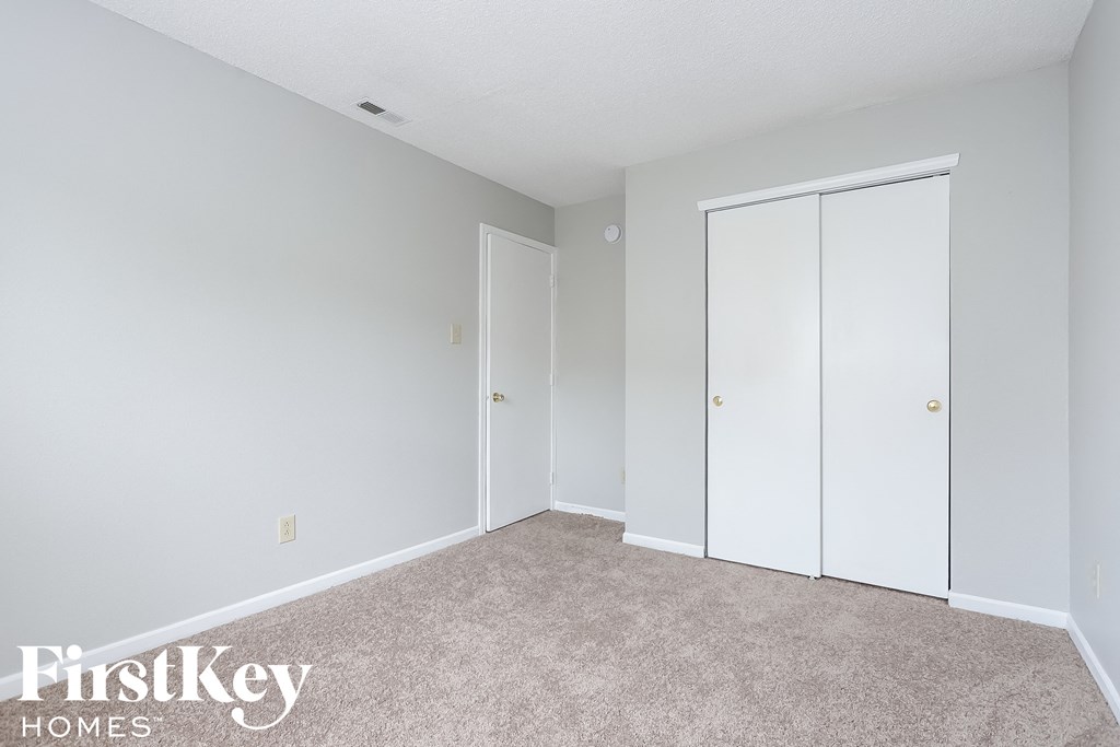 a bedroom with two closet doors and a carpeted floor