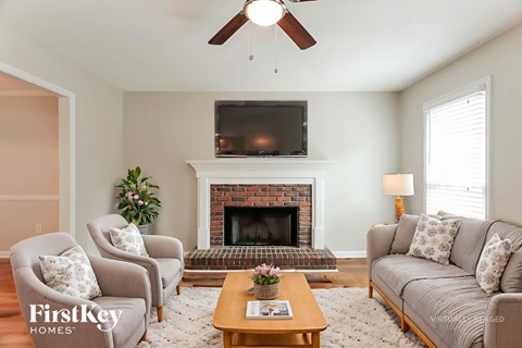 A living room with a fireplace and a flat screen TV mounted above it.