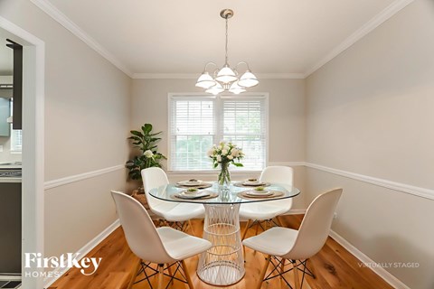 A dining room with a glass table and white chairs.