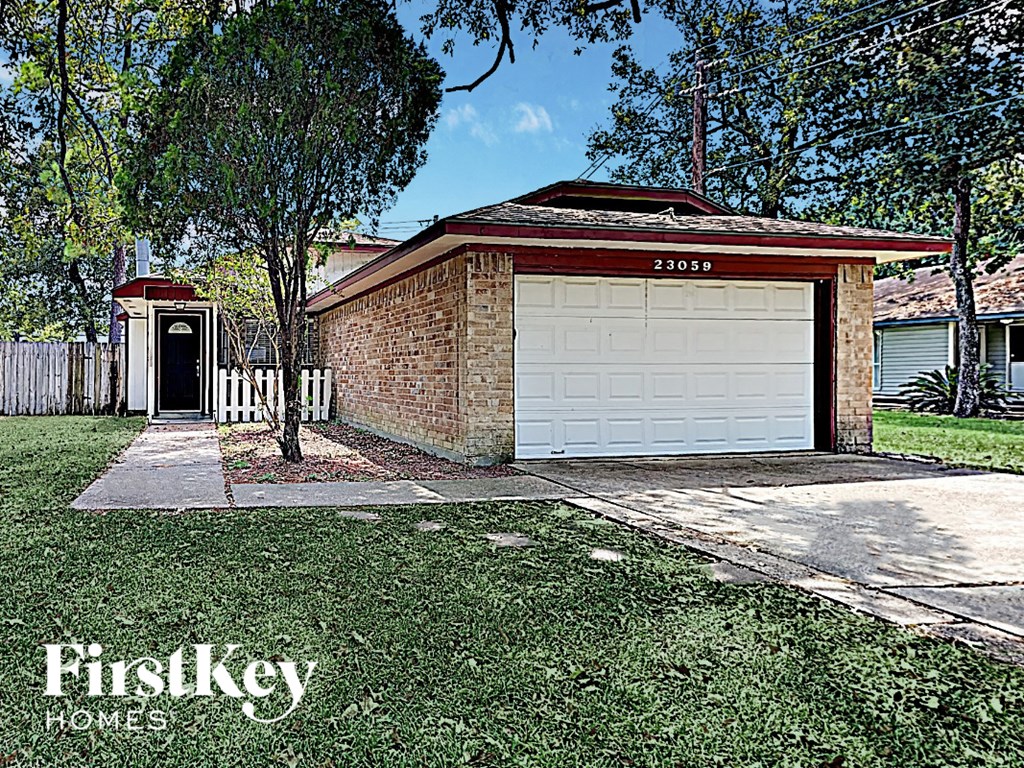 A brick house with a white garage door is for sale.